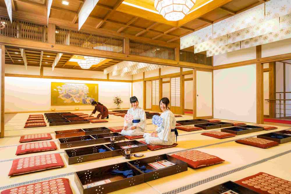 Tatami resting room at Dogo Onsen Annex Asuka-no-Yu with visitors in yukata seated on cushions
