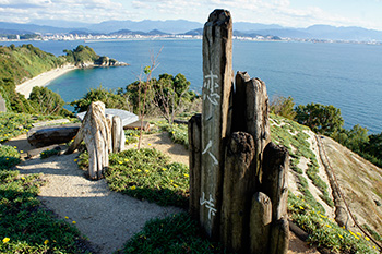A coastal path on Gogoshima Island with carved wooden posts overlooking a bay and the Seto Inland Sea