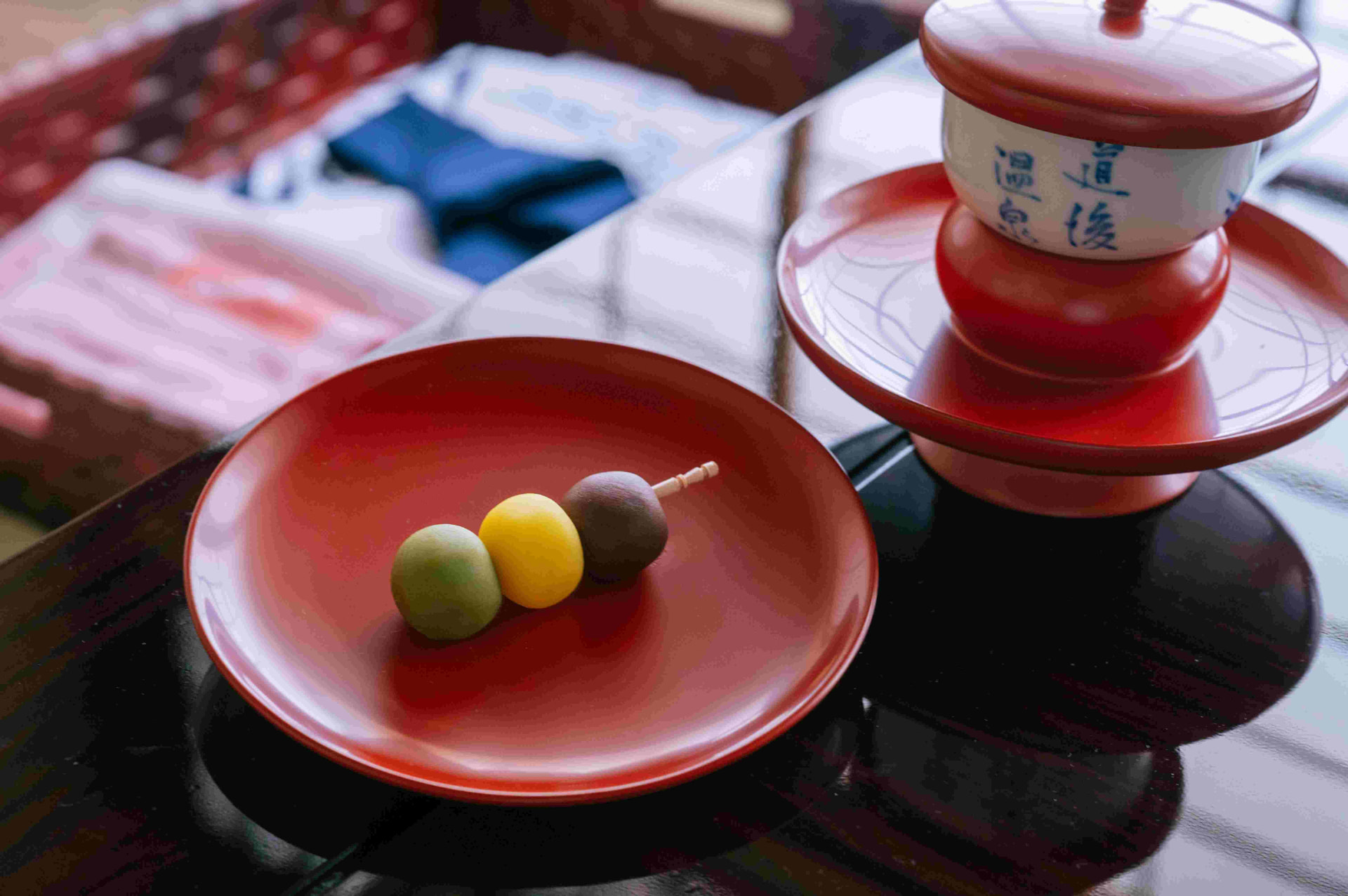 Three-coloured Botchan dango on a red lacquer plate with Dogo Onsen teacups